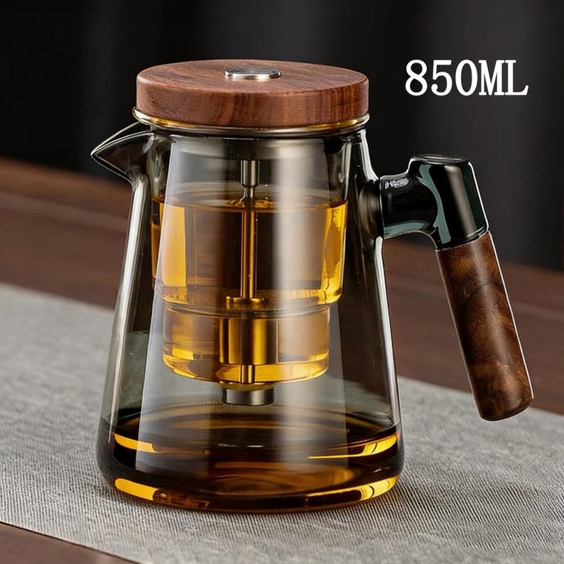 Pode incluir: Bule de vidro transparente com tampa e al&ccedil;a de madeira. O bule tem um infusor embutido e &eacute; preenchido com um l&iacute;quido dourado. Capacidade de 850 ml.
