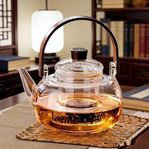 以下が含まれることがあります： 木製のハンドルと蓋が付いた透明なガラスのティーポット。 ティーポットには琥珀色の紅茶が入っており、織りのマットの上に置かれています。 ハンドルは木と革でできています。 ティーポットの内部にはガラスのインフューザーがあります。