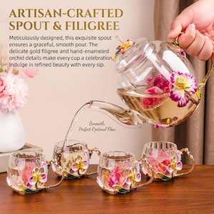 Puede incluir: Una tetera de cristal transparente y cuatro tazas a juego con asas de filigrana dorada y detalles de orquídeas esmaltadas a mano en tonos rosa, amarillo y verde. La tetera vierte líquido en las tazas, que contienen pétalos de flores rosas.