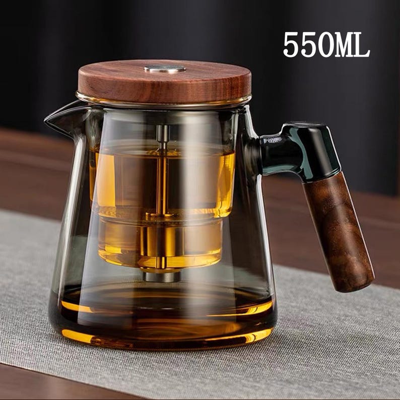 Pode incluir: Bule de vidro transparente com tampa e al&ccedil;a de madeira. Cont&eacute;m um l&iacute;quido dourado e um infusor interno. O texto "550ML" &eacute; vis&iacute;vel. Capacidade de 550 ml.