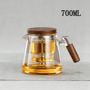 Pode incluir: Uma chaleira de vidro transparente com tampa e al&ccedil;a de madeira, cheia de l&iacute;quido &acirc;mbar. A chaleira tem um infusor embutido e est&aacute; rotulada como "700ML". A al&ccedil;a e a tampa s&atilde;o de madeira escura.