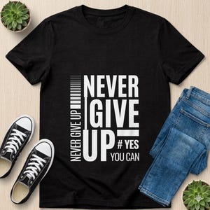 May include: Black t-shirt with the words "NEVER GIVE UP" in white block letters. The shirt also includes the text "# YES YOU CAN". The shirt is paired with black sneakers and blue jeans.