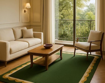 May include: A living room scene featuring a green rug with a scalloped yellow and cream border. A wooden coffee table and a beige sofa are in the room. A chair and a large window with a view of trees are also visible.