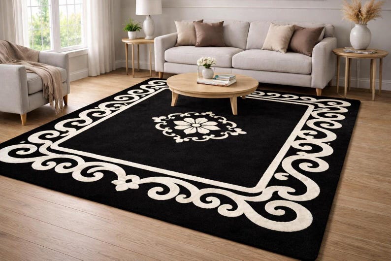 May include: A black area rug with a white floral design in the center and a white scrollwork border. The rug is rectangular and placed in a living room setting with a sofa, chairs, and a coffee table.