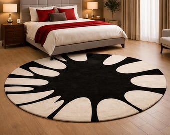 May include: A large circular area rug featuring a bold, high-contrast design with a solid black center and radiating cream-colored petal-like shapes extending toward the outer edge, creating a striking graphic pattern on the floor.