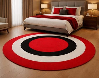 May include: A large, round rug with a bold design. The rug features concentric circles in red, black, and white. The rug is placed on a hardwood floor in a bedroom setting, with a bed and nightstands visible in the background.