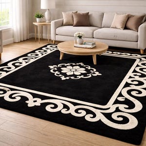 May include: A large, rectangular black area rug with a cream-colored border and central floral design. The border features a repeating scroll pattern. The rug is placed on a hardwood floor in a living room setting.
