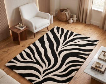 May include: A rectangular area rug featuring a high-contrast black and cream zebra stripe pattern. The design consists of organic, flowing lines that mimic natural animal markings, creating a bold visual texture across the entire surface.