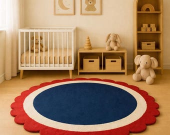 May include: A round rug with a scalloped edge in a nursery setting. The rug features a navy blue center, a white border, and a red scalloped edge. The room includes a white crib, wooden furniture, and framed artwork.