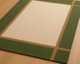 May include: A rectangular rug with a cream-colored center and a green border. A thin, tan-colored line frames the cream center and intersects the green border at the corners. The rug is placed on a wooden floor.