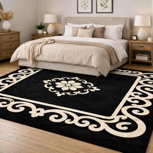 May include: A black rectangular area rug with a cream-colored border and a floral medallion. The rug is placed in a bedroom with a bed, nightstands, and a dresser. The rug's design adds a touch of elegance to the room.