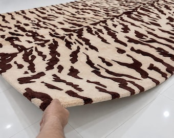 May include: A rectangular area rug featuring a high-contrast animal print pattern with dark brown, irregular, elongated shapes set against a light cream-colored background. The rug has a thick, textured pile and a soft, plush appearance.