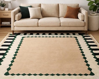 May include: A rectangular area rug featuring a solid beige center bordered by a geometric diamond pattern in dark green. The outer edge displays a repeating sequence of alternating black and beige vertical stripes, creating a structured border.