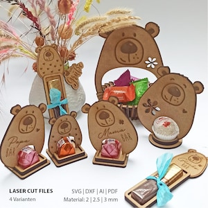 Könnte beinhalten: Verschiedene lasergeschnittene Geschenkhalter in Bärenform aus Holz. Einige halten Süßigkeiten, andere haben Texte wie "Papa BAR" und "Mama BAR". Ein korbförmiger Halter und ein Blumenarrangement sind ebenfalls vorhanden.