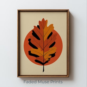 May include: A framed wall art print featuring a stylized oak leaf in shades of orange and brown, layered over a solid burnt orange circle on a cream background. The text Faded Muse Prints is visible at the bottom of the framed artwork.