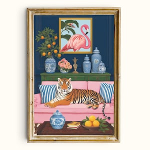 May include: A framed art print featuring a tiger lounging on a pink sofa. The artwork includes a flamingo painting, blue and white vases, and a table with oranges. The background is a dark blue wall with a gold frame.