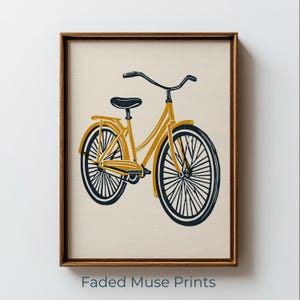 May include: A framed wall art print featuring a mustard yellow bicycle with dark navy blue wheels, handlebars, and seat. The bicycle is illustrated against a solid cream-colored background. The text Faded Muse Prints appears at the bottom.