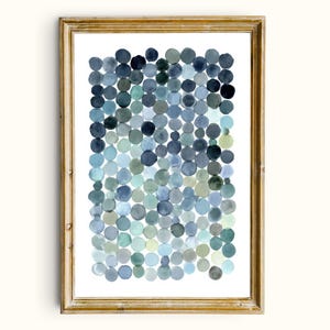 May include: Abstract watercolor art print in a gold frame. The artwork features a pattern of overlapping circles in shades of blue, teal, and gray. The circles vary in size and density, creating a textured effect. The overall aesthetic is modern and minimalist.