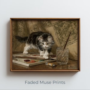 May include: A framed print of a kitten standing near a watercolor palette and a glass of water. The kitten has gray and white fur. A paintbrush rests in the glass. The print has a vintage aesthetic.