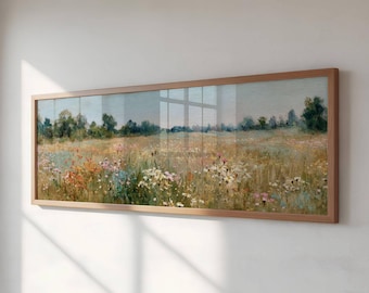 May include: A framed landscape painting depicting a field of wildflowers in shades of yellow, pink, and white. The artwork is set against a backdrop of trees and a soft blue sky. The frame is made of light brown wood.
