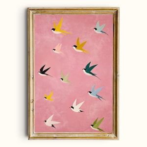 May include: A framed art print featuring a pink background with multiple colorful birds in flight. The birds are depicted in various colors, including yellow, black, green, and blue. The frame is gold-colored.