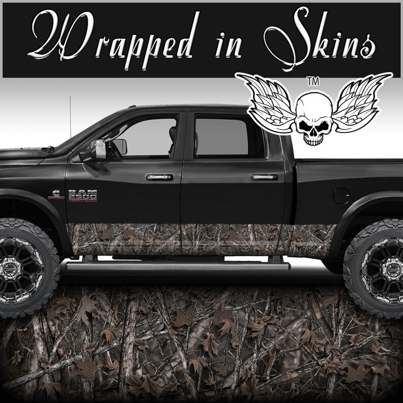 May include: Black pickup truck with a camouflage wrap on the lower portion of the doors. The truck has a skull with wings graphic on the back window. The text "Wrapped in Skins" is at the top of the image.