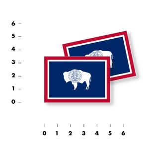 May include: Two stickers featuring the flag of Wyoming. The flag is blue with a white outline of a buffalo and the state seal in the center. The seal is a red circle with white lettering and a white star. The flag is bordered by a red stripe.