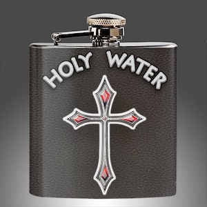 Puede incluir: Una petaca de plata con un acabado de cuero negro. La petaca tiene una tapa de plata y una cruz de plata con joyas rojas. Las palabras "HOLY WATER" están impresas en la petaca en blanco.