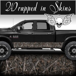 May include: Black pickup truck with a camouflage wrap on the lower portion of the doors. The truck has a skull with wings graphic on the back window. The text "Wrapped in Skins" is at the top of the image.