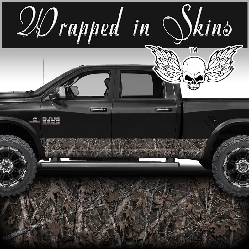 May include: Black pickup truck with a camouflage wrap on the lower portion of the doors. The truck has a skull with wings graphic on the back window. The text "Wrapped in Skins" is at the top of the image.
