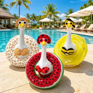 May include: Three novelty inflatable pool floats in the shape of geese, each with a hat, sunglasses, and bikini top. One has a leopard print, another a watermelon design, and the third is yellow. The background shows a swimming pool and palm trees.