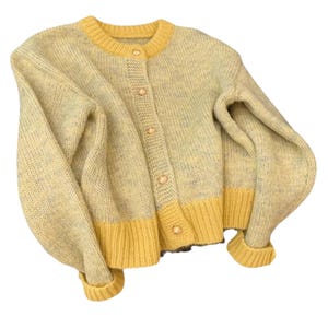 May include: A pale yellow cardigan with a round neck and long sleeves. The sweater has yellow trim on the collar, cuffs, and hem. It fastens with five pearl-effect buttons. A cosy knitwear item.