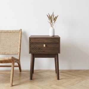 May include: A handmade wooden sign saying "Welcome" in a whimsical font. It has a distressed white background and a dark stained wooden frame. A small, decorative heart is attached to the sign.