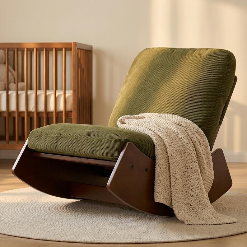 Pu&ograve; includere: Una moderna sedia a dondolo con struttura in legno marrone scuro e cuscini in velluto a coste verde oliva. Una coperta in maglia color crema &egrave; drappeggiata sul sedile. La sedia &egrave; su un tappeto rotondo colorato.