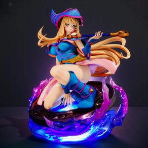 Può includere: Statuetta dettagliata di un personaggio femminile degli anime, in ginocchio con lunghi capelli biondi e che indossa un abito blu e rosa. Tiene in mano un bastone con la punta dorata. La base ha un effetto blu e viola brillante.