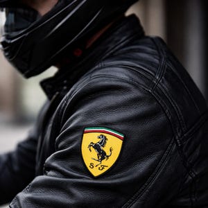 May include: Black leather motorcycle jacket with a Ferrari logo patch on the upper arm. The patch features a black prancing horse on a yellow background, with green, white, and red accents. The jacket has a quilted design.
