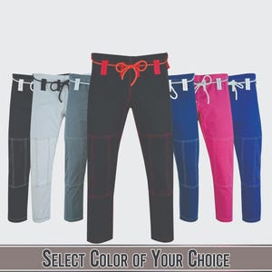 May include: A selection of martial arts pants in various colors, including black, gray, blue, and pink. Each pair features a drawstring waist and reinforced stitching. The text "SELECT COLOR OF YOUR CHOICE" is at the bottom.