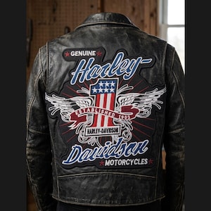 May include: Black leather motorcycle jacket with a distressed finish. The back features a large Harley-Davidson patch with the words "Genuine Harley-Davidson Motorcycles" and a patriotic design with wings, stars, and stripes. Established 1903.