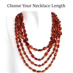 May include: A layered amber necklace with oval beads in shades of brown and orange, displayed on a white mannequin. The image includes the text "Choose Your Necklace Length" at the top.