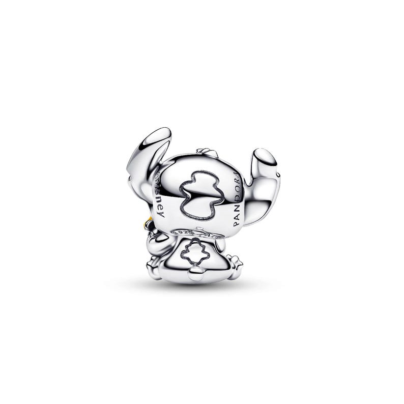 A silver-colored charm in the shape of a cartoon character, with the text "STELLA" visible on it.