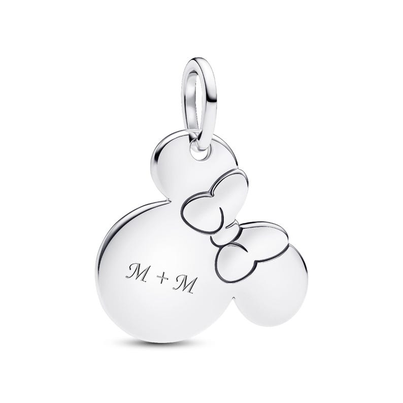 A silver charm in the shape of a Mickey Mouse with two bows, and the text "M + M" engraved on it.