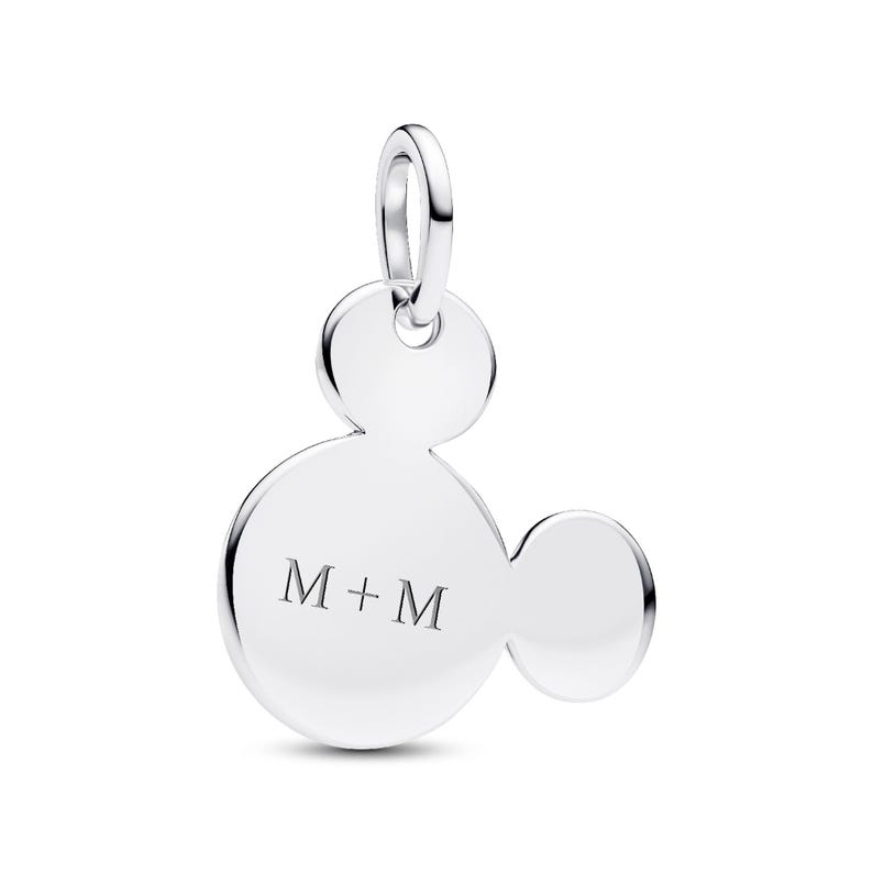 A silver-colored charm in the shape of a Mickey Mouse, with the letters "M+M" engraved on it.