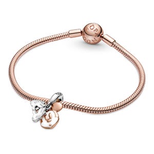 A rose gold-colored bracelet with a charm and a bead attached to it.