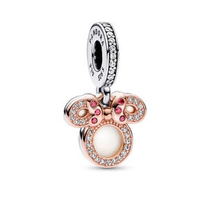 A pendant in the shape of a bow with a white center and pink and red gemstones.