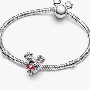 A silver bracelet with a charm in the shape of a cartoon character, specifically Mickey Mouse.
