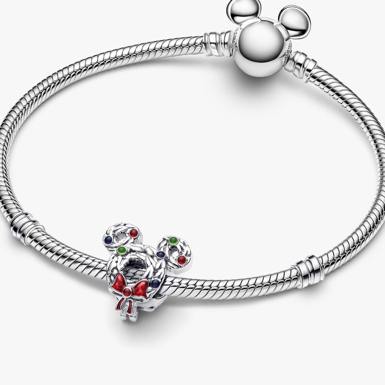 A silver bracelet with a charm in the shape of a cartoon character, specifically Mickey Mouse.