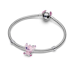 A silver bracelet with two charms on it, one of which is a pink character resembling Stitch from the Disney movie Lilo & Stitch.