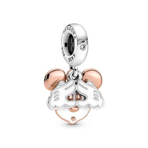 A silver and gold pendant charm in the shape of a cartoon mouse, with a heart-shaped charm attached to it.