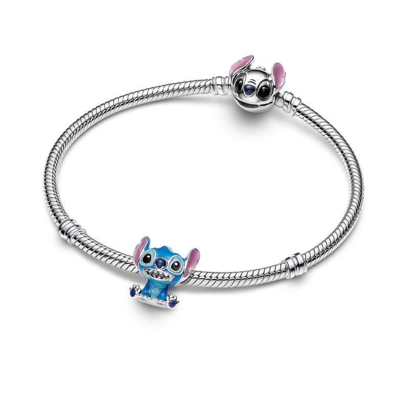 A silver bracelet with two charms on it, one of which is a blue cartoon character.
