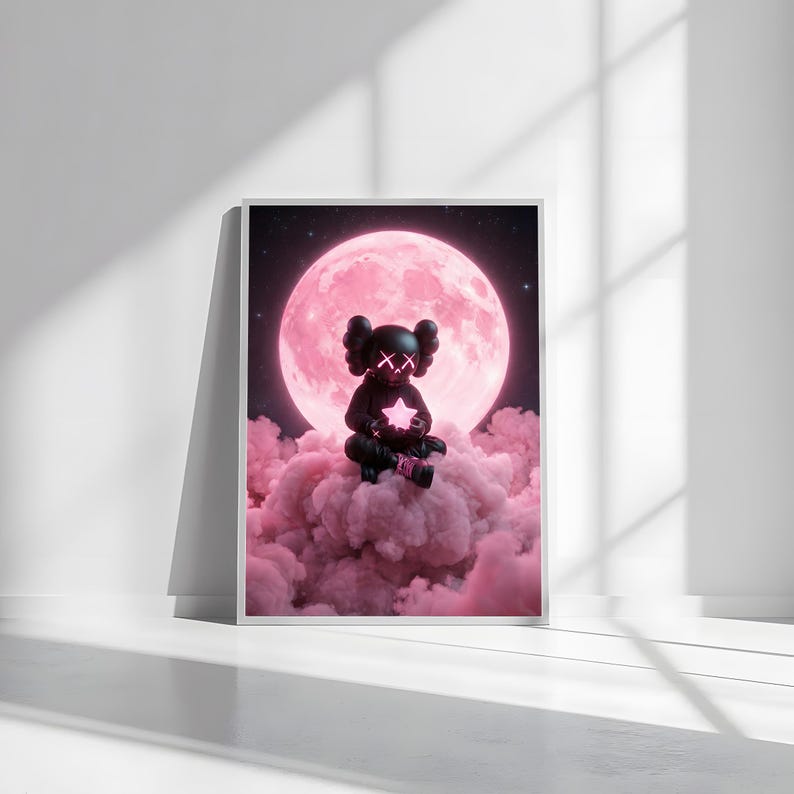 May include: Framed art print showing a black figure with 'X' eyes holding a glowing star, sitting on pink clouds. A large pink moon and starry night sky are in the background. The artwork is presented in a white frame.